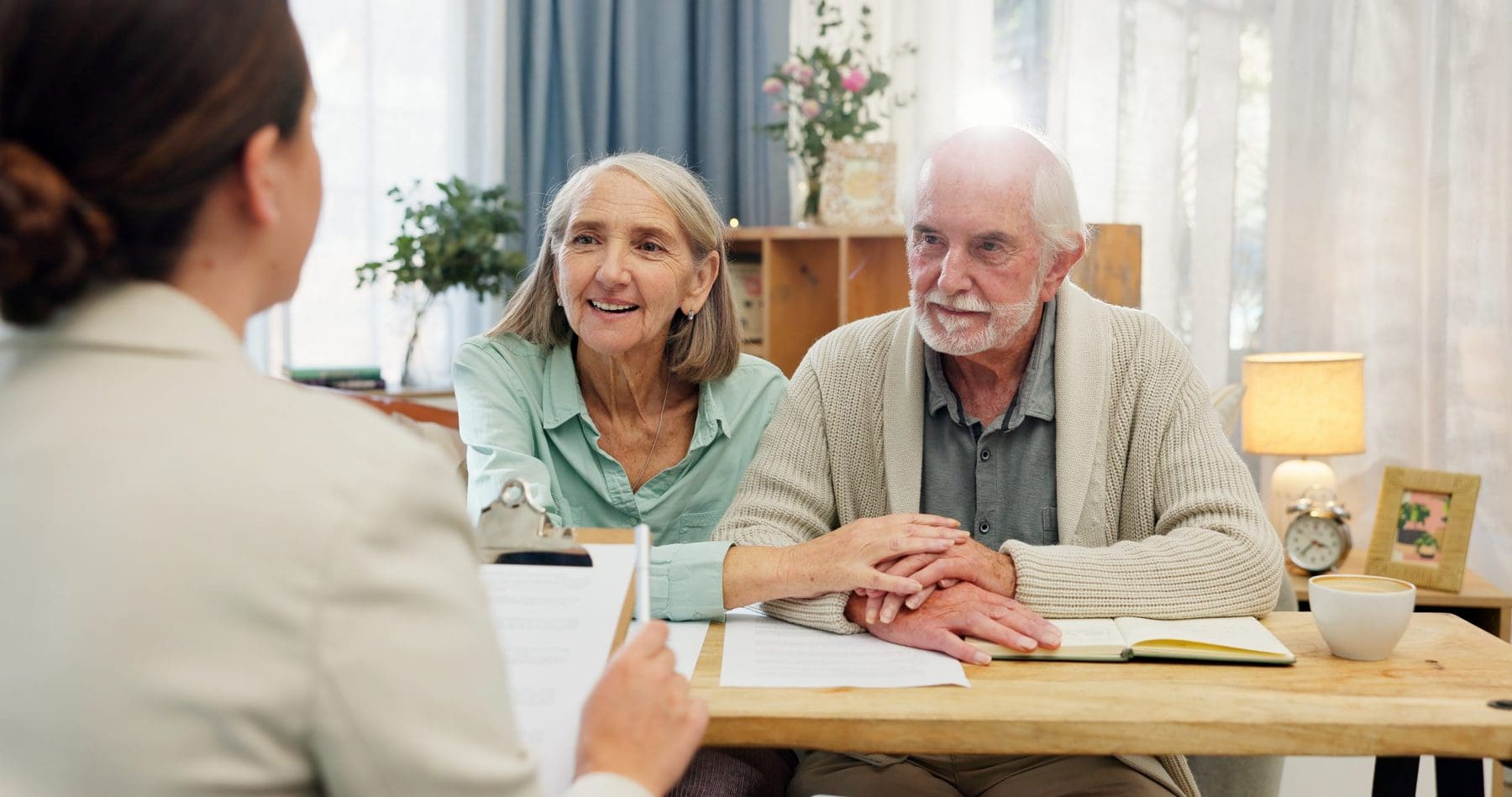 Elder man and woman in lounge speaking to young man.