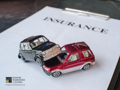 Two small toy cars crashed over paper with words insurance.