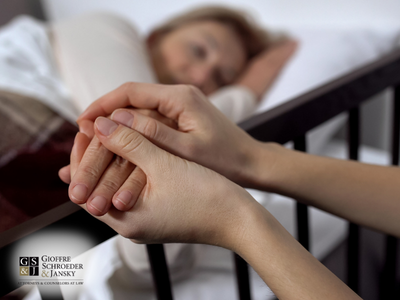 Woman laying in bed. Another person holding her hand.