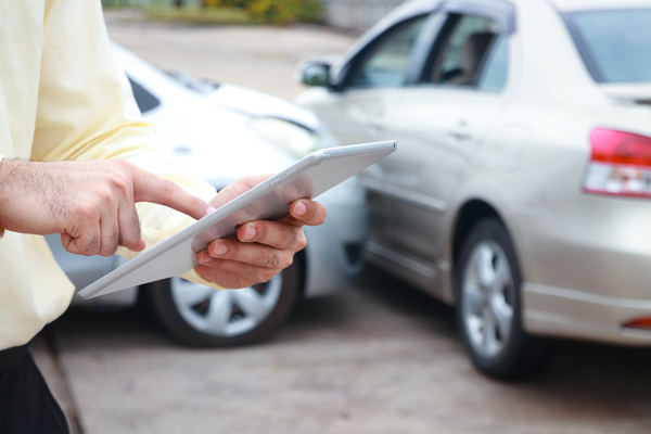 Person using tablet. Car accident on the background.