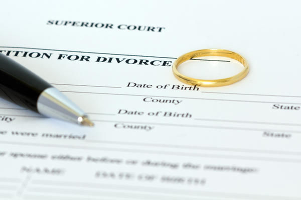 Divorce papers with weeding band and pen on top.